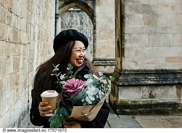portrait of beautiful Asian lady smiling holding flowers and coffee