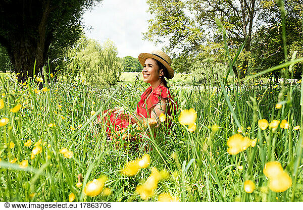 portrait of beautiful Asian woman sat in a field enjoying the sunshine