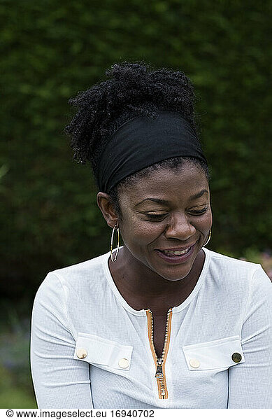 Portrait of black woman sitting in a garden  smiling during alternative therapy session.