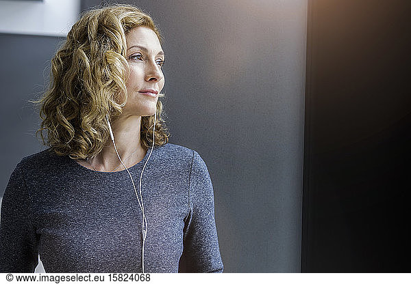 Portrait of blond businesswoman with earphones in office