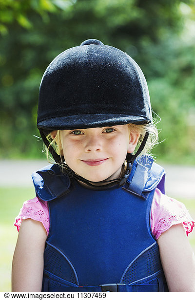 Portrait of blond girl wearing riding hat.