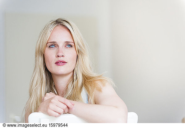 Portrait of blond woman leaning on back rest looking at distance