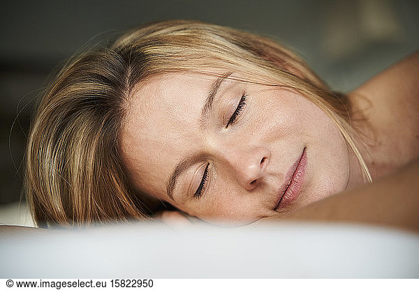 Portrait of blond young woman lying down with closed eyes