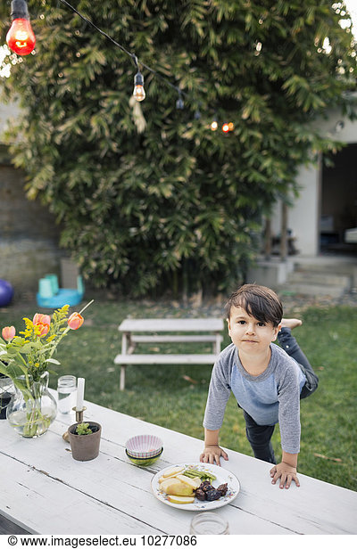 Portrait of boy leaning on table at yard