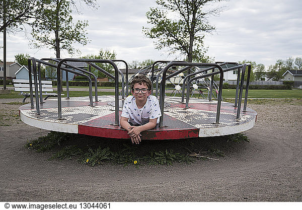 Portrait of boy lying on merry-go-round at playground