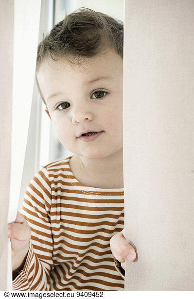 Portrait of boy playing with curtain
