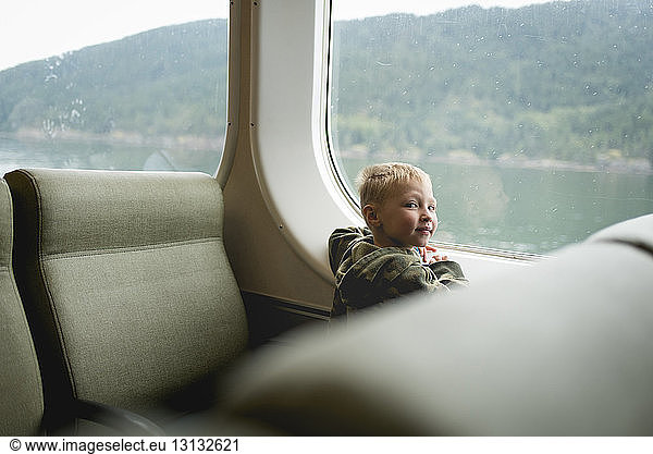 Portrait of boy sitting by window while travelling in train