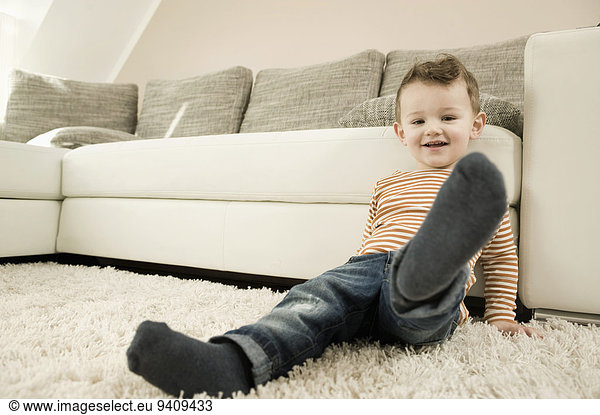 Portrait of boy sitting on rug  smiling