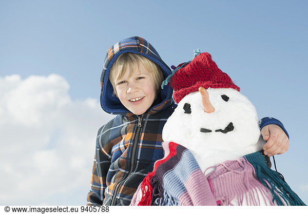 Portrait of boy standing with snowman  smiling