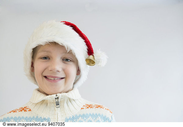 Portrait of boy wearing santa hat against white background  close up