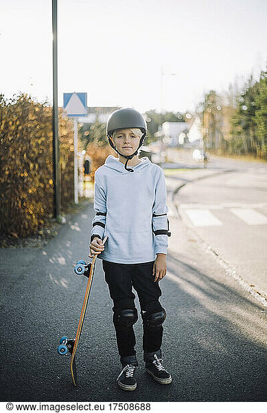 Portrait of boy white skateboard standing on road