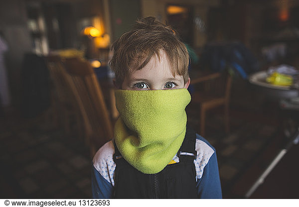 Portrait of boy with mouth covered by scarf at home