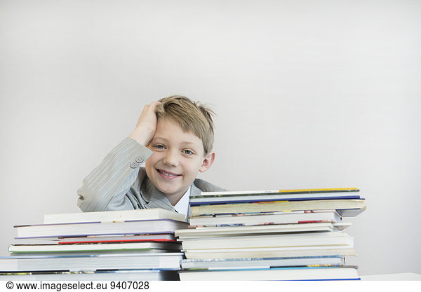 Portrait of boy with stack books  smiling