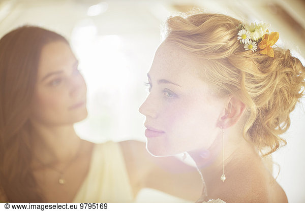Portrait of bride with bridesmaid in background in domestic room