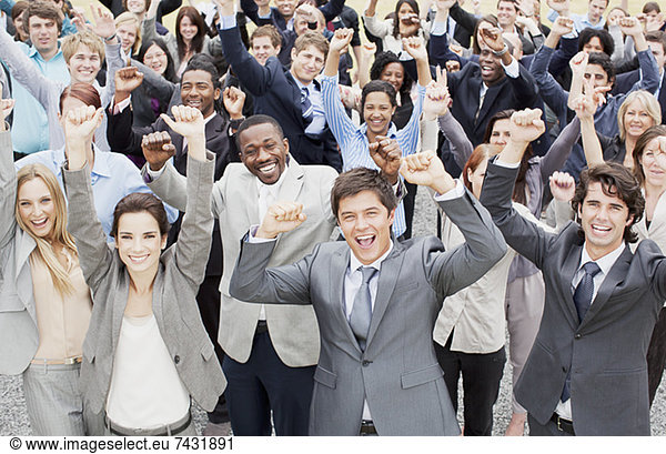 Portrait of business people cheering with arms raised in crowd