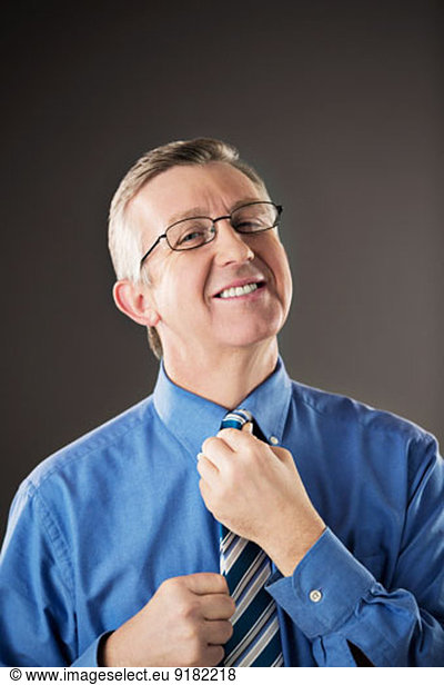 Portrait of businessman adjusting his tie