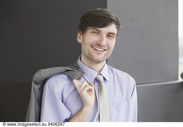 Portrait of businessman holding suit  smiling