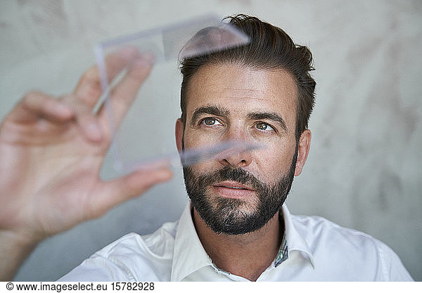 Portrait of businessman looking at transparant cube