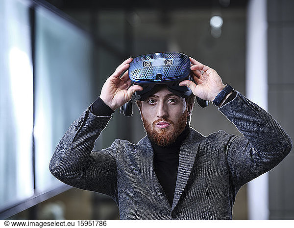 Portrait of businessman taking off VR glasses in modern office