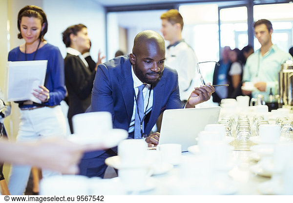 Portrait of businessman using laptop during coffee break at conference