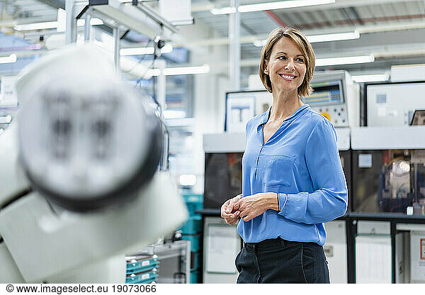 Portrait of businesswoman at assembly robot in a factory