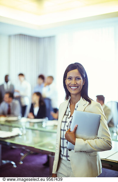 Portrait of businesswoman holding laptop in conference room