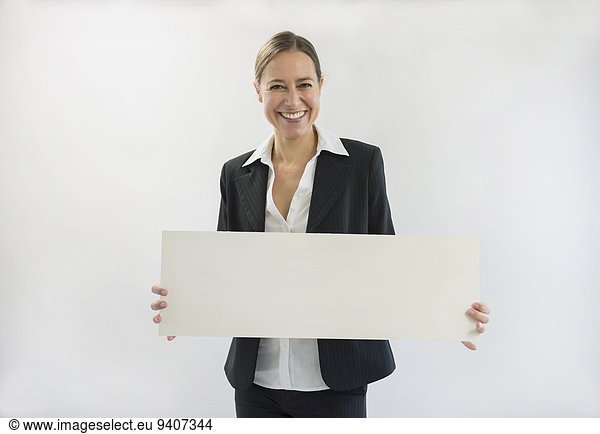 Portrait of businesswoman in black suit holding blank placard  smiling