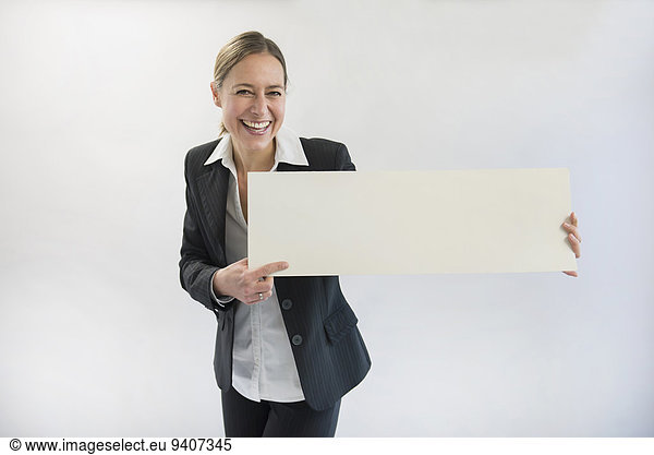Portrait of businesswoman in black suit holding blank placard  smiling