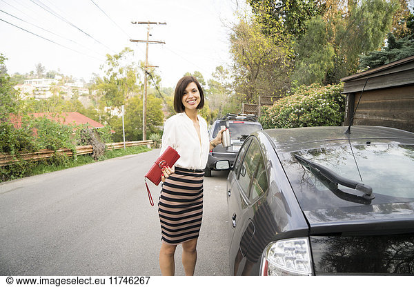 Portrait of businesswoman next to car on suburban street