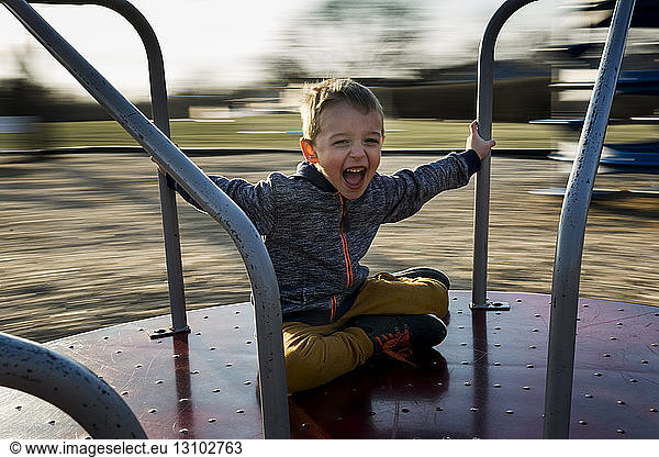 Portrait of cheerful boy sitting on merry-go-round