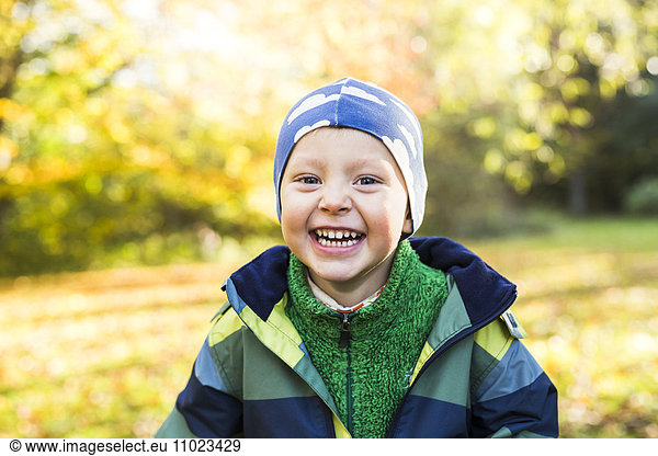 Portrait of cheerful boy wearing warm clothing in forest