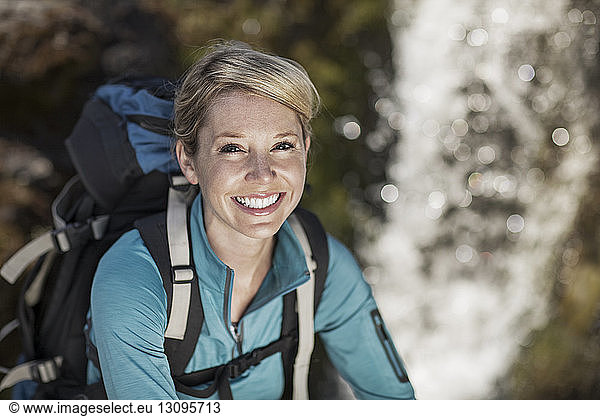 Portrait of cheerful female hiker carrying backpack