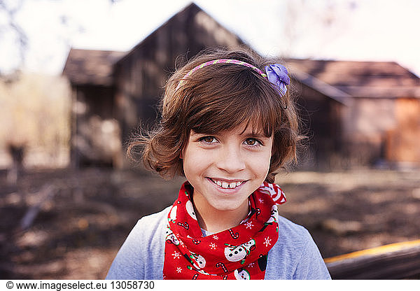 Portrait of cheerful girl standing against house