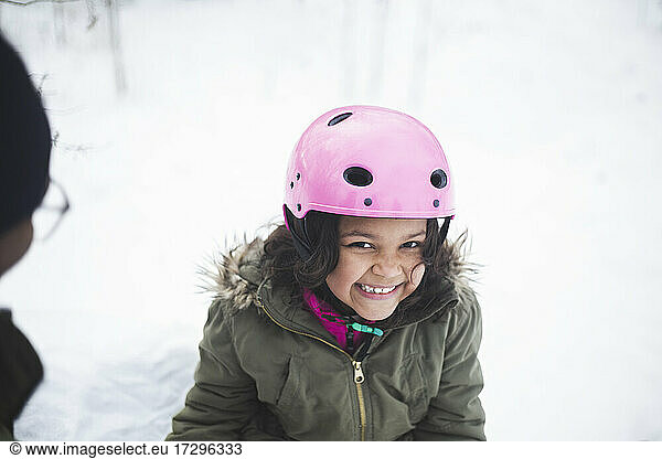 Portrait of cheerful girl wearing pink helmet during winter