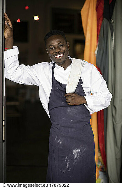 Portrait of cheerful restaurant owner standing at doorway