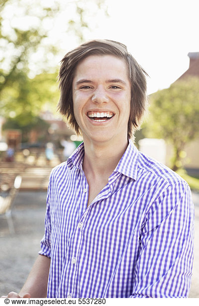 Portrait of cheerful teenage boy laughing outdoors