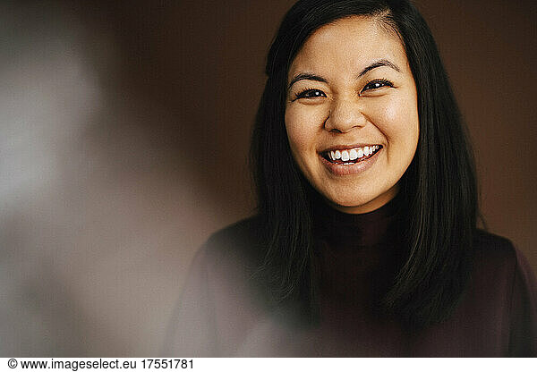 Portrait of cheerful woman against brown background