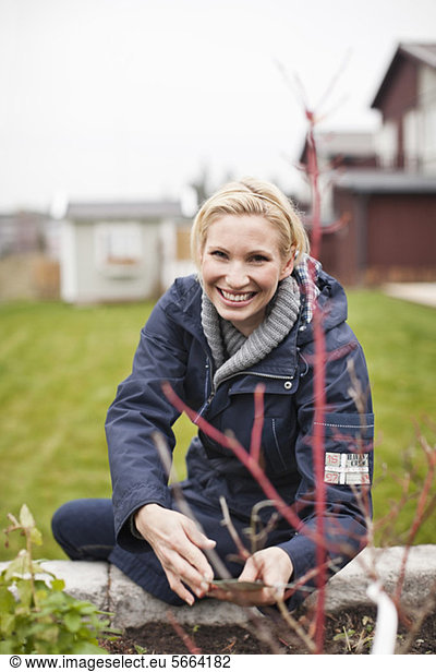 Portrait of cheerful woman gardening in back yard