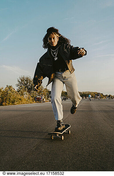 Portrait of cheerful woman skating on road in park