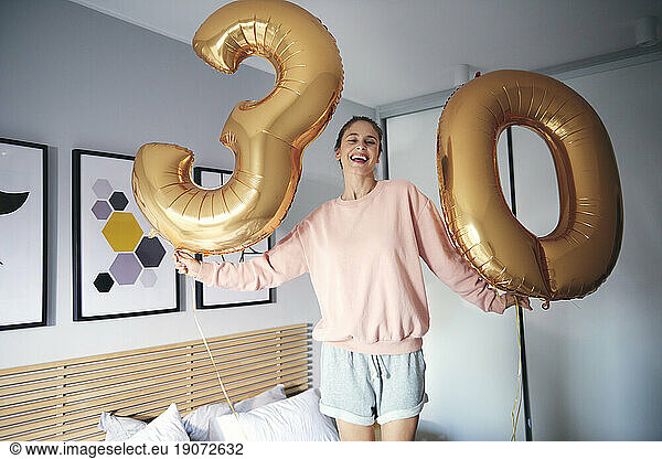 Portrait of cheerful woman with golden balloons  celebrating her birthday