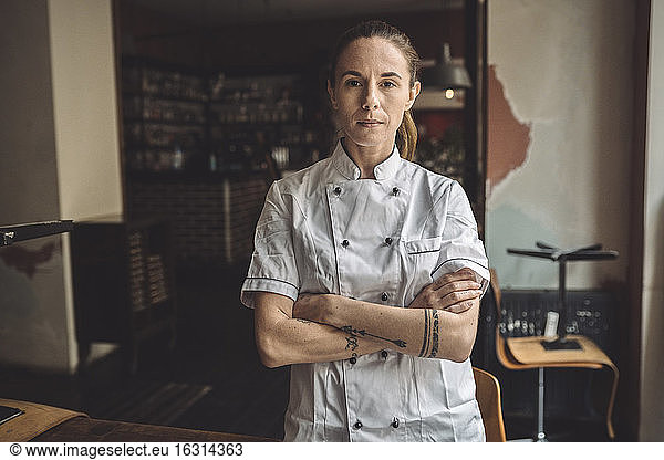 Portrait of chef with arms crossed standing in restaurant
