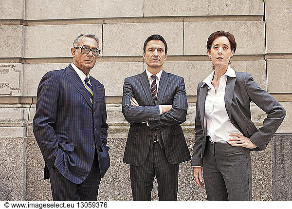 Portrait of confident business people standing against wall