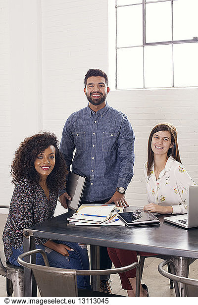 Portrait of confident business professionals at table in office