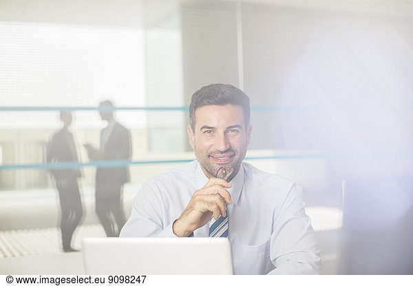 Portrait of confident businessman at laptop in office