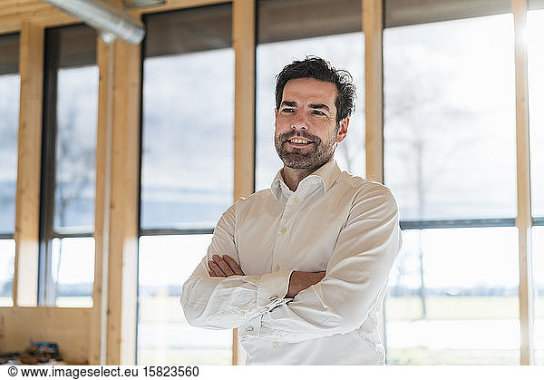 Portrait of confident businessman at the window in open-plan office