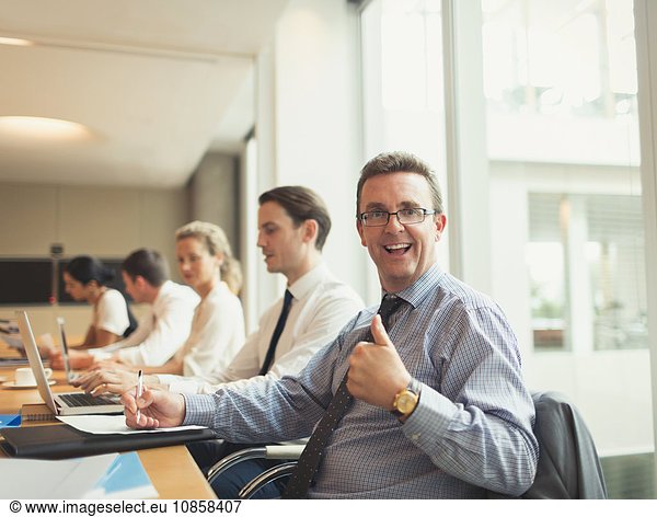 Portrait of confident businessman gesturing thumbs-up in conference room meeting