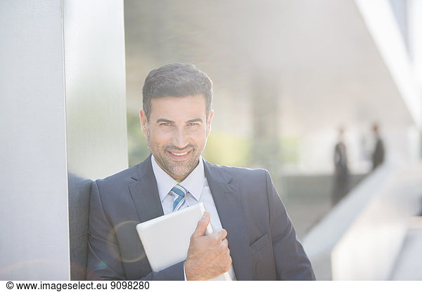 Portrait of confident businessman holding digital tablet outdoors