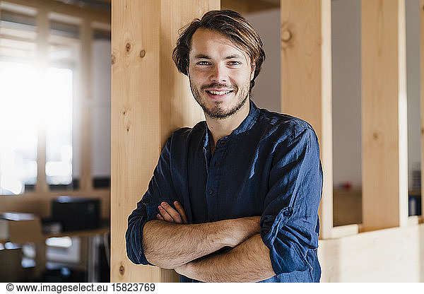 Portrait of confident businessman in wooden open-plan office