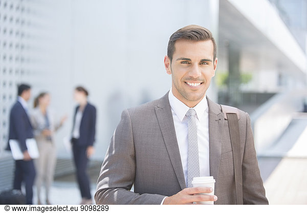 Portrait of confident businessman with coffee outdoors