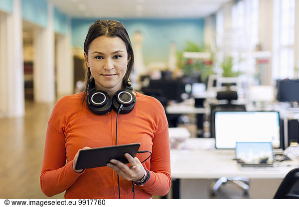 Portrait of confident businesswoman holding digital tablet in creative office